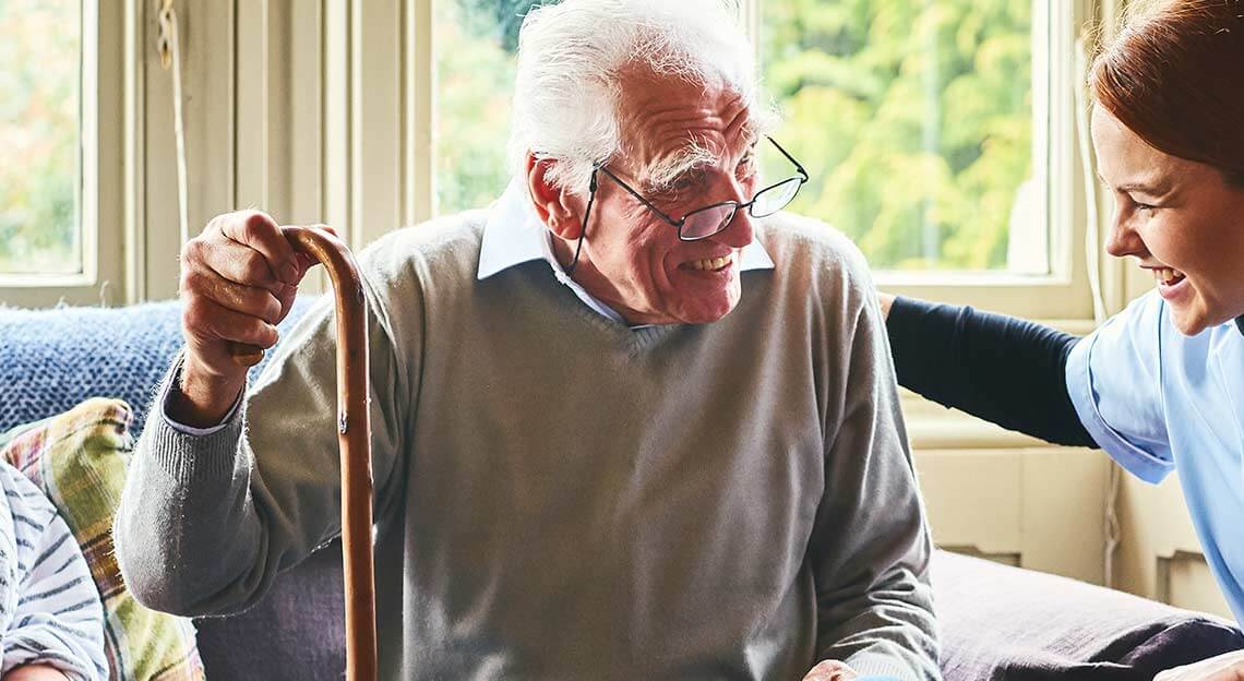 Senior man smiling at laughing Heartis caretaker.